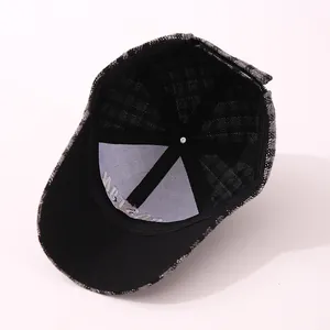 Detail view of the thick plaid flannel fabric and internal stitching of the baseball cap