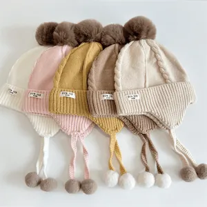 Flat lay of colorful baby knit hats with pom-poms and earflaps in various soft autumn shades
