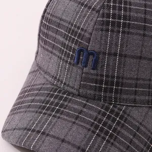 Close-up of premium grey plaid fabric with 3D embroidered blue letter M on baseball cap