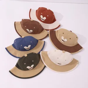 Detailed flat lay of corduroy kids bucket hats with bear patches in six assorted colors