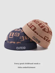 Close-up of corduroy brimless dock caps for kids in navy and khaki with CUTE embroidery