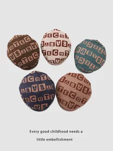 Flat lay of colorful corduroy baby berets featuring cute letter patterns for autumn
