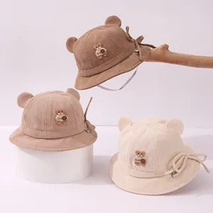 Three corduroy baby bucket hats with bear ears in brown, beige, and cream colors