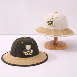 Detail of corduroy texture and bear patch on beige and green kids bucket hats