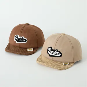 Detail of baby baseball caps with Baston letter embroidery and corduroy brim textures
