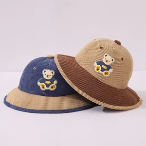Detailed texture of kids' corduroy bucket hat with a cute cartoon bear badge
