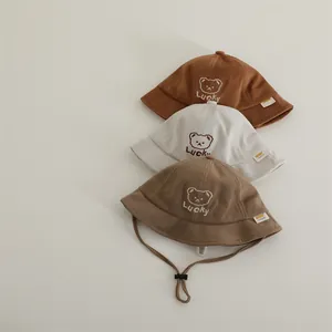 Three children's LUCKY bear bucket hats in caramel, beige, and brown with chin straps