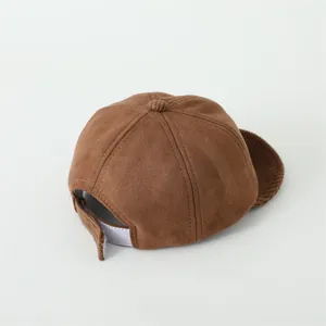 Detail der braunen Baby-Basecap mit Wildleder-Textur, Cord-Schirm und Klettverschluss-Riemen