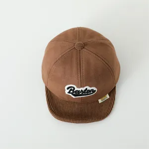 Top view of brown suede baby baseball cap with corduroy brim and Baston embroidery