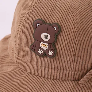 Close-up of brown corduroy bucket hat texture with cute rubber bear patch and KKJ logo