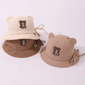 Detail of corduroy baby bucket hats with bear ears and chin straps in neutral colors