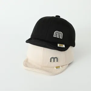 Detail of soft cotton baby baseball caps with corduroy brims and letter M patches