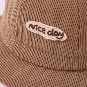 Close-up of khaki corduroy texture and Nice Day embroidery on children bucket hat