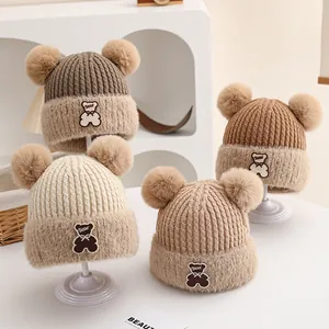 Detail of four double-pom winter beanies for kids with embroidered bear patches