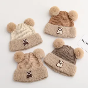 Winter knit baby hats with double pompoms and cute bear patches in earthy tones