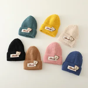 Detalle de siete colores de gorros de punto para bebé con parches de ositos