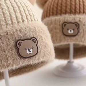 Detailed view of the soft faux fur brim and cute bear emblem on a knit baby winter hat