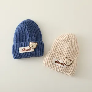 Detalle de la textura de punto de gorros para niños con ositos de peluche y texto THE DREAM