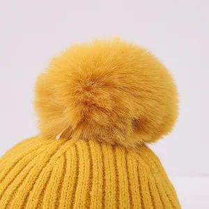 Detailaufnahme der hellgelben Strickmütze mit flauschigem Bommel und Rippenstrickmuster