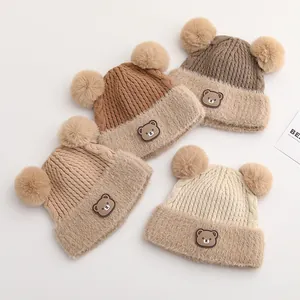 Detailed view of four winter knit beanies with fluffy double pom-poms and bear patches