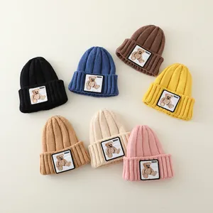 Close-up of knit texture and teddy bear patch on colorful winter baby hats