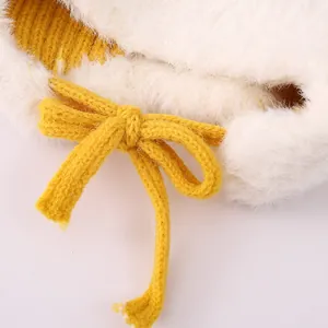 Detail der Plüsch-Kunstfellstruktur und gelben Strickschleife an der Kinder-Wintermütze