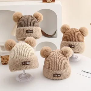 Detail of baby winter knit hats with double pom-poms and leather smile face patches