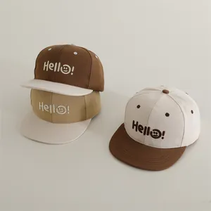 Dettaglio di cappellini bicolore con ricamo Hello e smiley su tessuto in twill