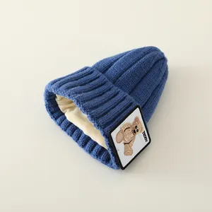 Detail of warm knit baby hat with teddy patch and soft cream-colored fleece lining