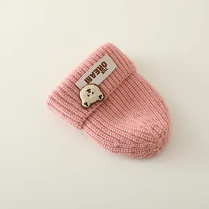 Detalle de gorro de punto rosa para bebé con parche de oso y bordado de THE DREAM