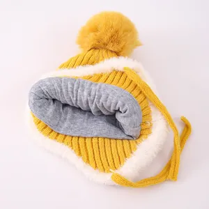 Detailansicht der Kinder-Strickmütze mit großem Bommel und warmen Kunstfell-Ohrenklappen