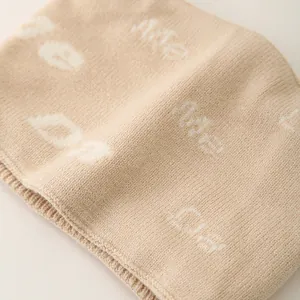 Close-up of beige knit baby hat set with soft texture and white letter jacquard pattern