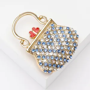 Broche sac à main de luxe avec cristaux bleus et fermoir cœur rouge sur socle doré