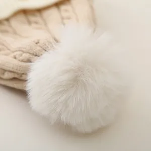 Detailed macro view of the fluffy faux fur pom-pom and thick cable knit wool hat