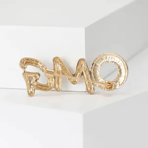 Macro detail of the gold-plated PMO letter brooch with textured finish on white block