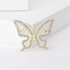 Gros plan d'une broche papillon dorée avec strass incrustés et perles élégantes