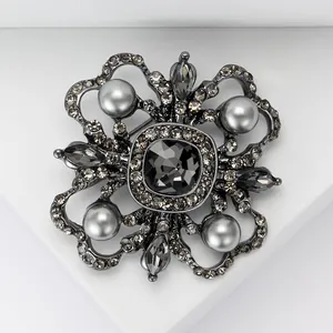Macro detail of vintage baroque floral brooch with grey crystals and pearls on white stand