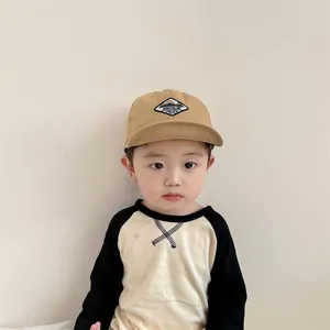 Khaki baby baseball cap with mountain embroidery worn by child model in casual setting