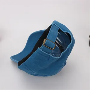 Detail of adjustable brass buckle and fabric strap on a blue cotton baseball cap