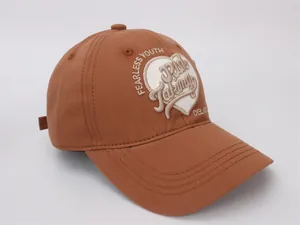 Détail d'une casquette de baseball caramel avec broderie de cœur et Fearless Youth