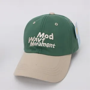 Detail of white 3D embroidery on a green and beige cotton twill baseball cap