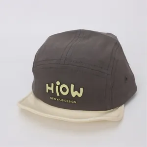 Macro detail of dark grey camper hat with beige brim and yellow HIOW 3D logo