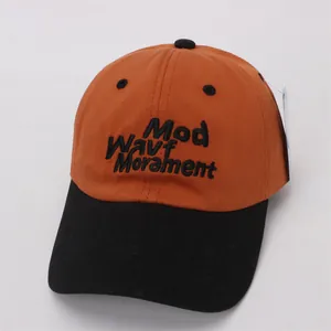 Close-up of orange and black color-block baseball cap with 3D embroidery detail