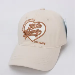 Gros plan sur la broderie de cœur et le lettrage d'une casquette de baseball en coton beige