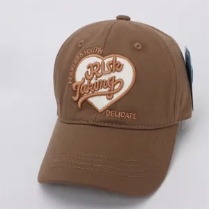 Détail d'une casquette marron avec broderie Fearless Youth et écusson en forme de coeur
