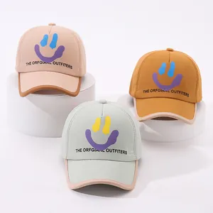 Three trendy kids baseball caps in beige, yellow and green with melting smiley face print