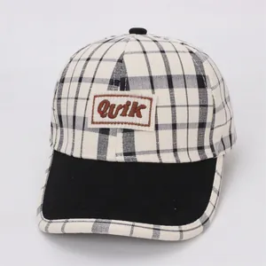 Détail de casquette de baseball à carreaux avec broderie Quik et visière noire