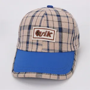 Détail de la casquette à carreaux avec broderie Quik bleue et motif de grille beige