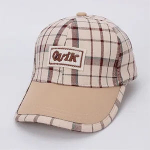 Détail de la casquette de baseball beige à carreaux pour enfants avec broderie Qvik et visière