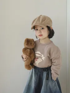 Detail view of child model wearing a light brown beret and matching sweatshirt set